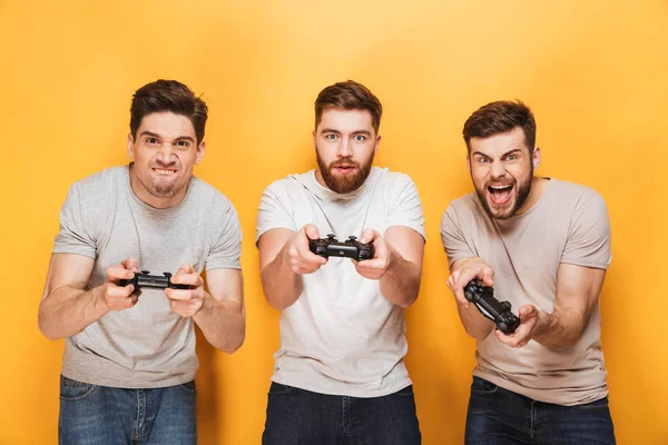 Трое Молодых Возбужденных Мужчин Держащих Руках Джойстики Играя Видеоигры Изолированные — стоковое фото