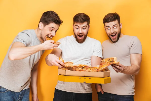 Трое Молодых Веселых Мужчин Едят Большую Пиццу Желтом Фоне — стоковое фото