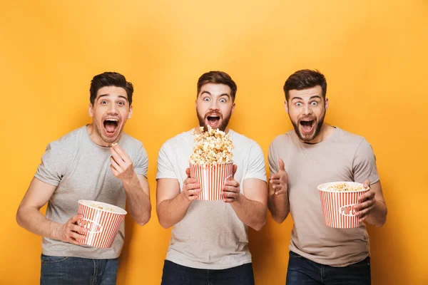 Three Young Cheerful Men Eating Popcorn Celebrating Isolated Yellow Background — Stock Photo, Image