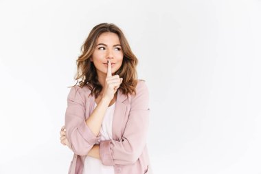 Bir kenara sessizlik jest gösterilen arka plan beyaz duvar bakmaktan izole duran genç güzel kadın görüntüsünü.