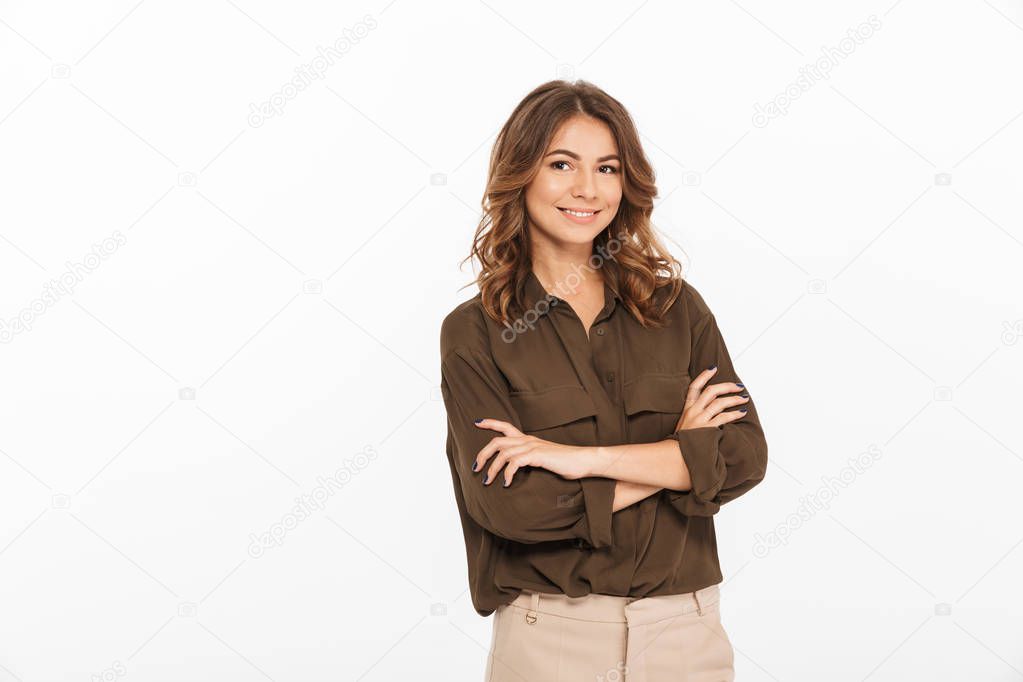 Portrait of a smiling young woman standing with arms folded isolated over white background