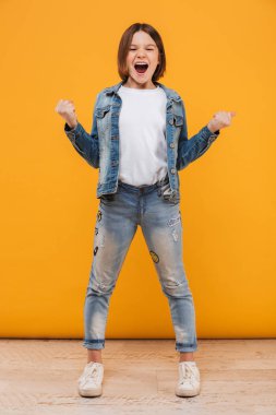 Tam uzunlukta sarı arka plan üzerinde çığlık bir heyecan küçük kız öğrenci portresi