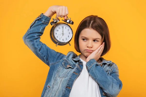 Portrait Upset Little Schoolgirl Holding Alarm Clock Yellow Background — Stock Photo, Image