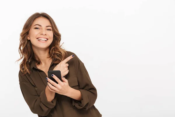 Porträtt Leende Ung Kvinna Håller Mobiltelefon Och Pekar Finger Bort — Stockfoto