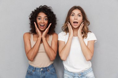 Portre iki genç kadın birlikte ayakta ve çığlık gri arka plan üzerinde izole heyecanlı