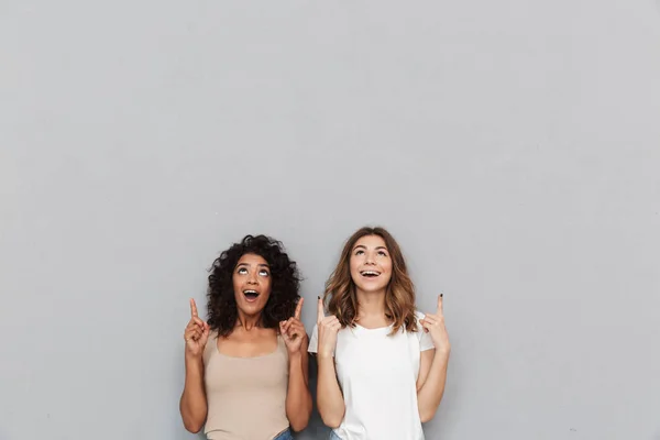 Retrato Dos Jóvenes Alegres Pie Juntas Apuntando Hacia Espacio Copia —  Fotos de Stock