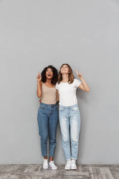 Полнометражный Портрет Двух Веселых Молодых Женщин Стоящих Вместе Указывающих Пространство — стоковое фото