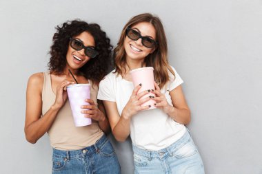 İki 3d gözlük plastik bardak gri arka plan üzerinde izole tutan genç kadınlarda gülümseyen portresi