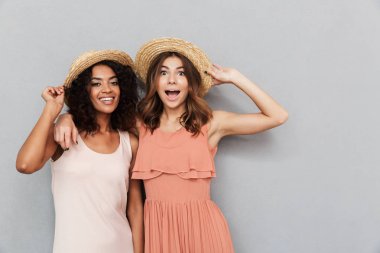 Yaz elbise gri arka plan üzerinde izole kamera bakarak iki genç kadın gülümseyerek portresi giymiş