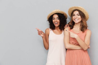 Yaz elbise gri arka plan üzerinde izole kopya alanı gösteren iki genç kadın gülümseyerek portresi giymiş