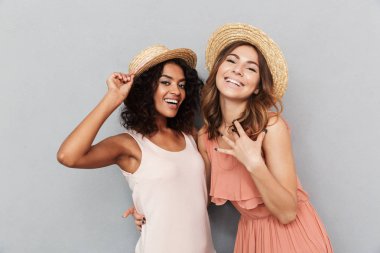 Gri arka plan üzerinde izole kamera bakarak yaz elbise giymiş iki mutlu genç kadın portresi