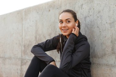 Fotoğraf mutlu güzel genç Asyalı açık havada dinleme müzik oturan kadın spor.