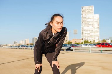 Görüntü şaşırtıcı Genç Asyalı kadın runner ayakta açık havada dinleme müzik spor.