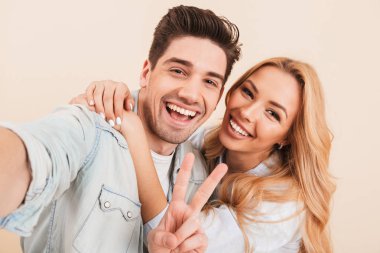İki mutlu insanlar erkek ve kadın üzerinde sarı arka plan izole gülümseme ile barış işareti gösterilen süre selfie fotoğrafta portre