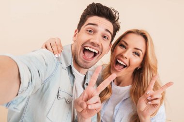 İki mutlu insanlar adam ve sarılma ve sarı arka plan üzerinde izole kamera barış işareti gülümseme ile gösterilen süre selfie fotoğrafta kadın fotoğrafı