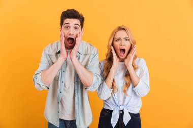 Şok insanlar erkek ve kadın açık ağızlı sarı arka plan üzerinde izole sürpriz ya da korkudan ifade temel giyim görüntü