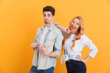 Fotoğraf, gülen ve having fun sarı arka plan üzerinde izole kadın, parmakla adam modern gençlerin