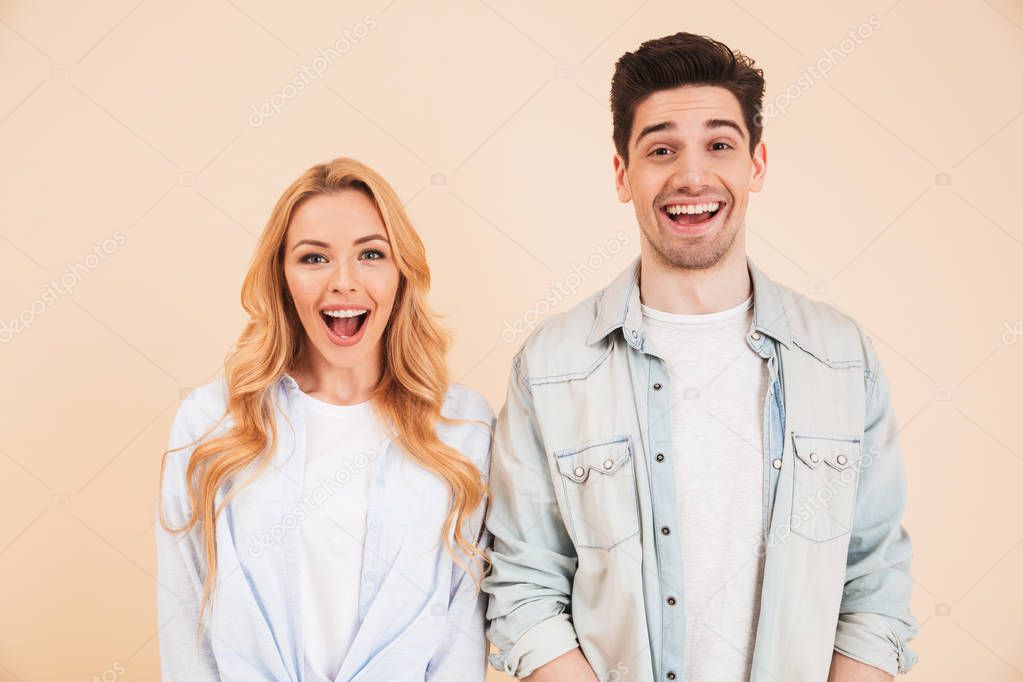 Portrait of beautiful young couple man and woman in basic clothing looking at you with happy smile isolated over beige background