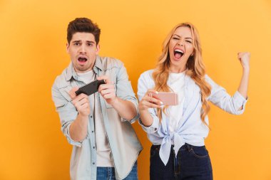 Birlikte oynayan ve video oyunları üzerinde sarı arka plan izole akıllı telefonlar üzerinde yarışan kaybeden adam ve kazanan kadın görüntüsünü
