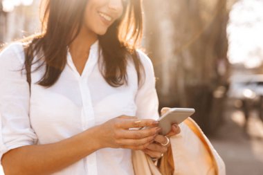 Cropped görüntünün mutlu esmer kadının smartphone açık havada gömlek yazma iletide resim