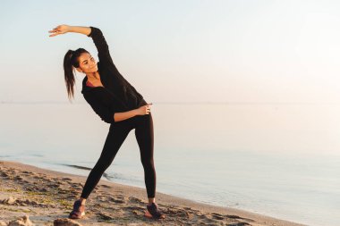 Genç ve güzel sporcumuz germe yapıyor deniz kenarında sabah egzersizleri