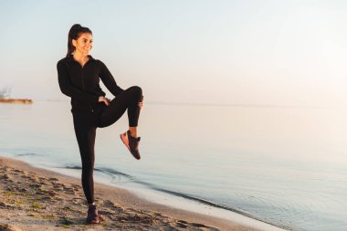 İnce genç sporcumuz sabah deniz kenarında germe egzersizleri yapıyor