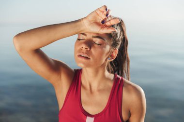 Yorgun sporcumuz alnının sahilde dururken koşu sonra silinerek