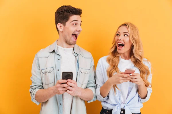 Mutlu Çift Erkek Birbirine Bakarak Akıllı Telefonlar Üzerinde Sarı Arka — Stok fotoğraf
