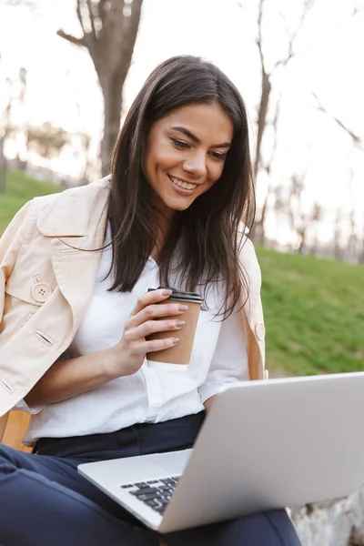 Mujer Joven Feliz Usando Ordenador Portátil Mientras Está Sentado Banco — Foto de Stock