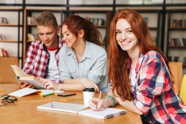 Hareket eden telefon ile kütüphanede otururken ödev neşeli Genç Grup