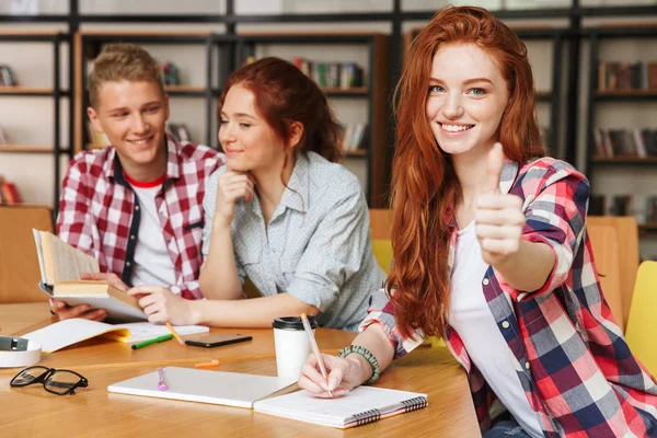 Gruppe Lächelnder Teenager Die Hausaufgaben Machen Während Sie Mit Handy — Stockfoto