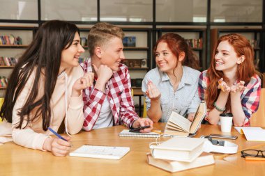 Cep telefonu ve kitap ile kütüphanede otururken ödev gençler gülen grubu