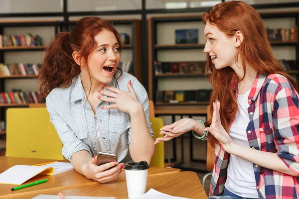 Retrato Duas Adolescentes Felizes Conversando Enquanto Estavam Sentadas Biblioteca — Fotografia de Stock