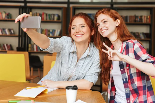 Selfie Cep Telefonu Ile Kütüphanede Otururken Alarak Iki Neşeli Genç — Stok fotoğraf
