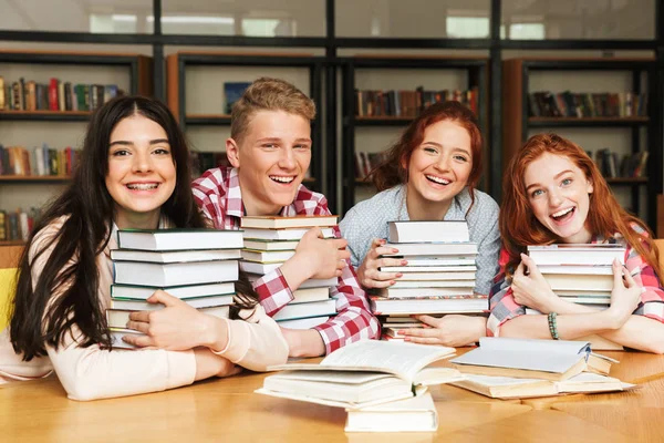 Grupo Adolescentes Felizes Sentados Mesa Biblioteca Com Grandes Pilhas Livros — Fotografia de Stock