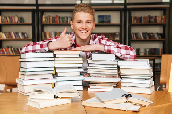 Garoto Adolescente Sorridente Sentado Mesa Biblioteca Com Grandes Pilhas Livros — Fotografia de Stock