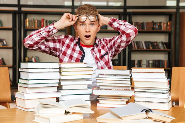 Surpreendido Adolescente Sentado Mesa Biblioteca Com Grandes Pilhas Livros — Fotografia de Stock