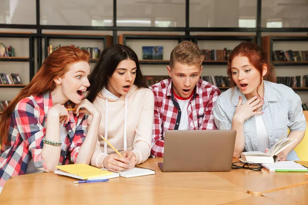 Grupa Nastolatków Podekscytowany Odrabiania Lekcji Siedząc Bibliotece Patrząc Ekran Laptopa — Zdjęcie stockowe