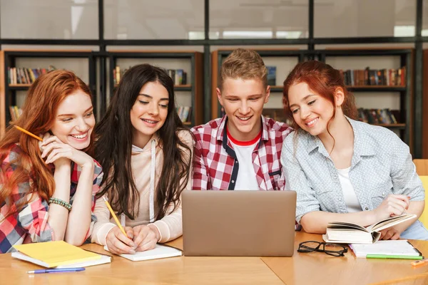 Grupa Nastolatków Uśmiechający Się Odrabiania Lekcji Siedząc Bibliotece Patrząc Ekran — Zdjęcie stockowe
