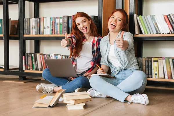 Duas Adolescentes Confiantes Sentadas Chão Estante Livros Uma Biblioteca Fazendo — Fotografia de Stock