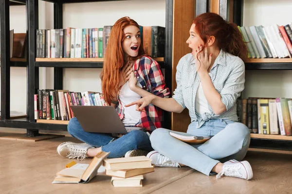 Duas Meninas Adolescentes Surpresas Sentadas Chão Estante Livros Uma Biblioteca — Fotografia de Stock