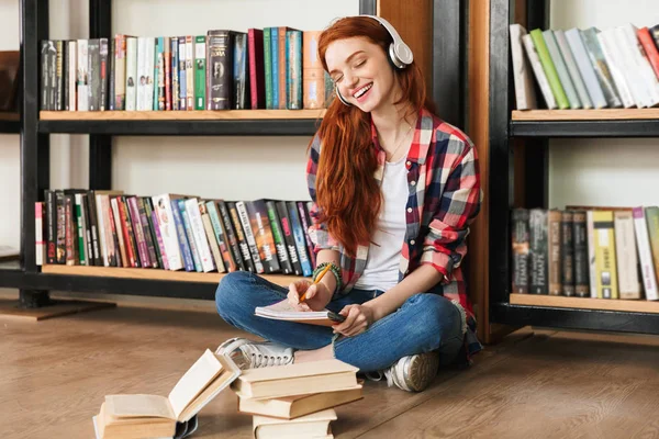 Lachende Tienermeisje Huiswerk Terwijl Zittend Bibliotheek Luisteren Naar Muziek Met — Stockfoto