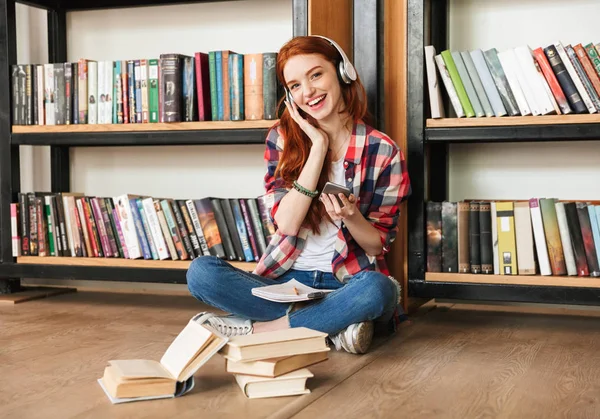 Vrolijke Tienermeisje Huiswerk Terwijl Zittend Bibliotheek Het Luisteren Naar Muziek — Stockfoto