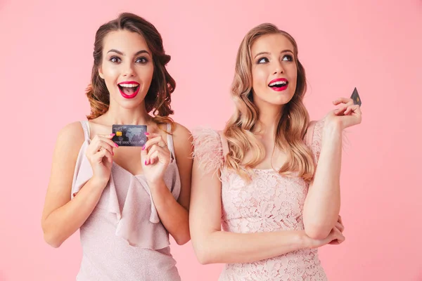 Twee Geïntrigeerd Vrouwen Jurken Poseren Met Creditcards Rondkijken Roze Achtergrond — Stockfoto
