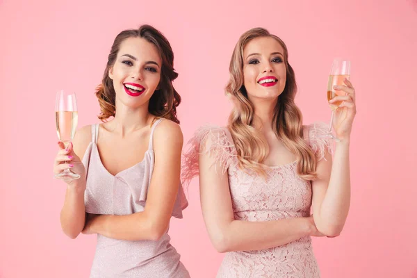 Две Счастливые Элегантные Женщины Платьях Позируют Вместе Шампанским Смотрят Камеру — стоковое фото