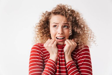 Korkunç sarışın kıvırcık kadın kazak tutarak ve uzak gri arka plan üzerinde seyir rahat kıyafetler içinde