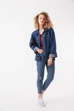 Tam boy görüntü güzel sarışın kıvırcık kadın kol cebinde ile gri arka plan üzerinde kameraya bakarken poz denim giysileri