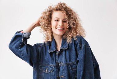 Poz ve beyaz arka plan üzerinde izole kamera bakarak denim ceket bir gülümseyen genç kız portresi