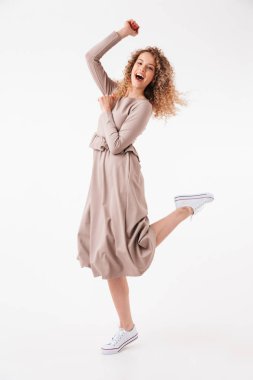 Tam boy görüntü eğleniyor ve kameraya gri arka plan üzerinde seyir içinde neşeli sarışın kıvırcık kadın