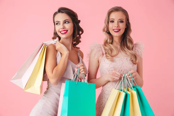 Dos Mujeres Sonrientes Vestidos Sosteniendo Paquetes Mientras Posan Juntas Sobre —  Fotos de Stock